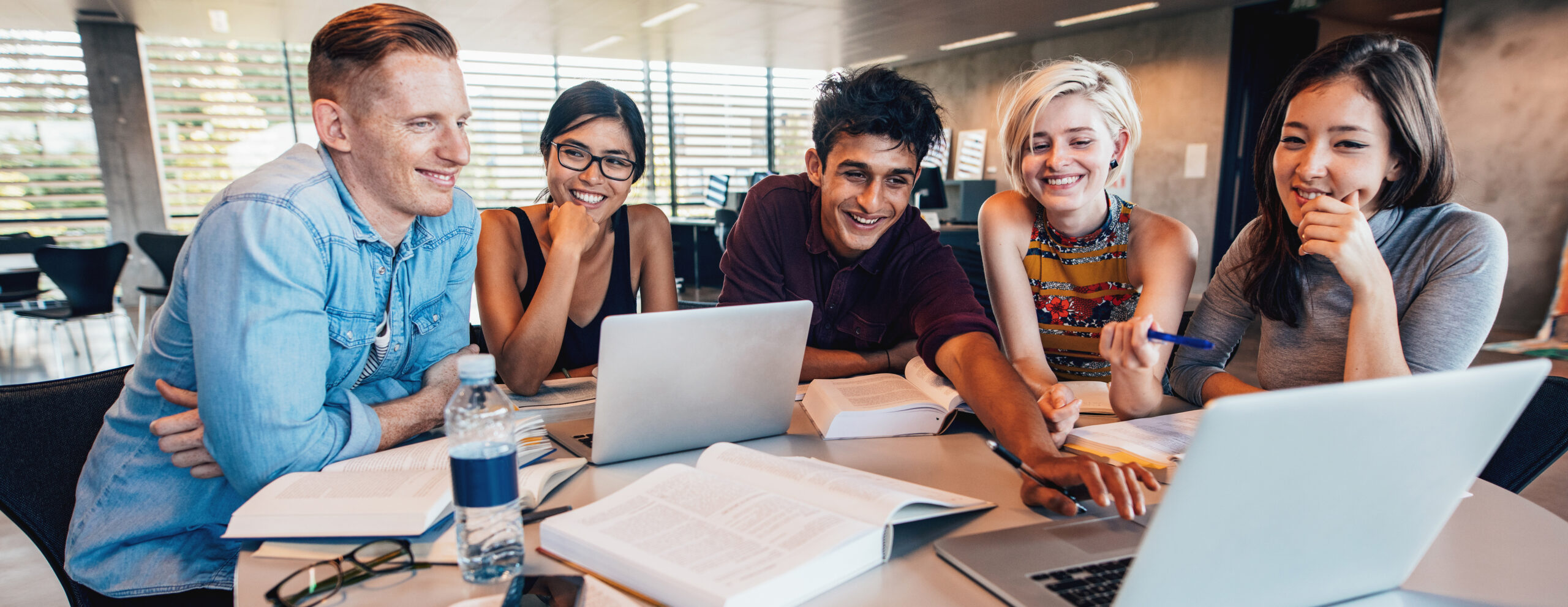 Group of students smiling and working on assignments together