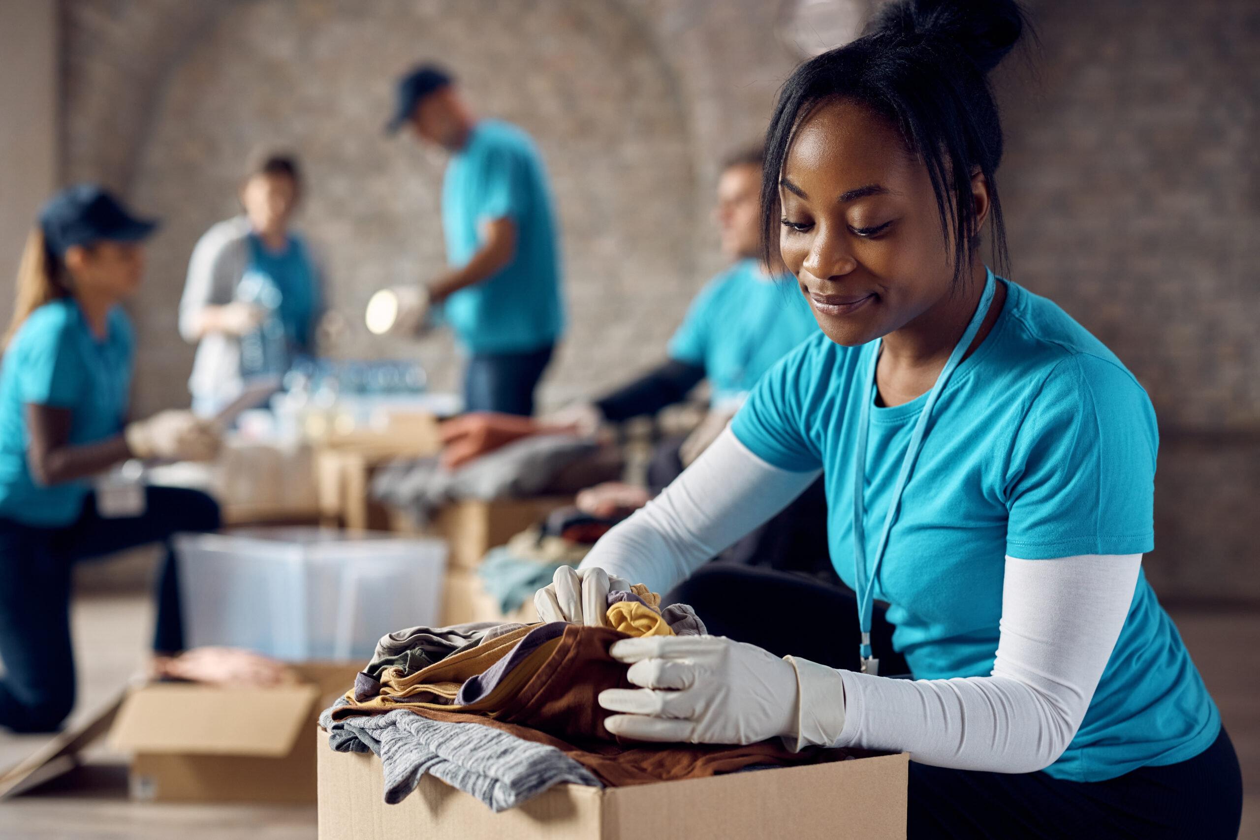 Young woman looking at donated clothing while working with non-profit