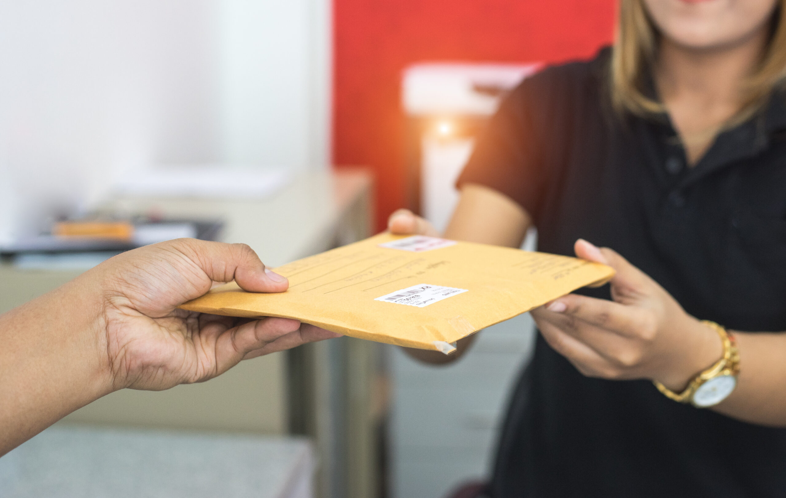 Man handing woman a shipping envelope